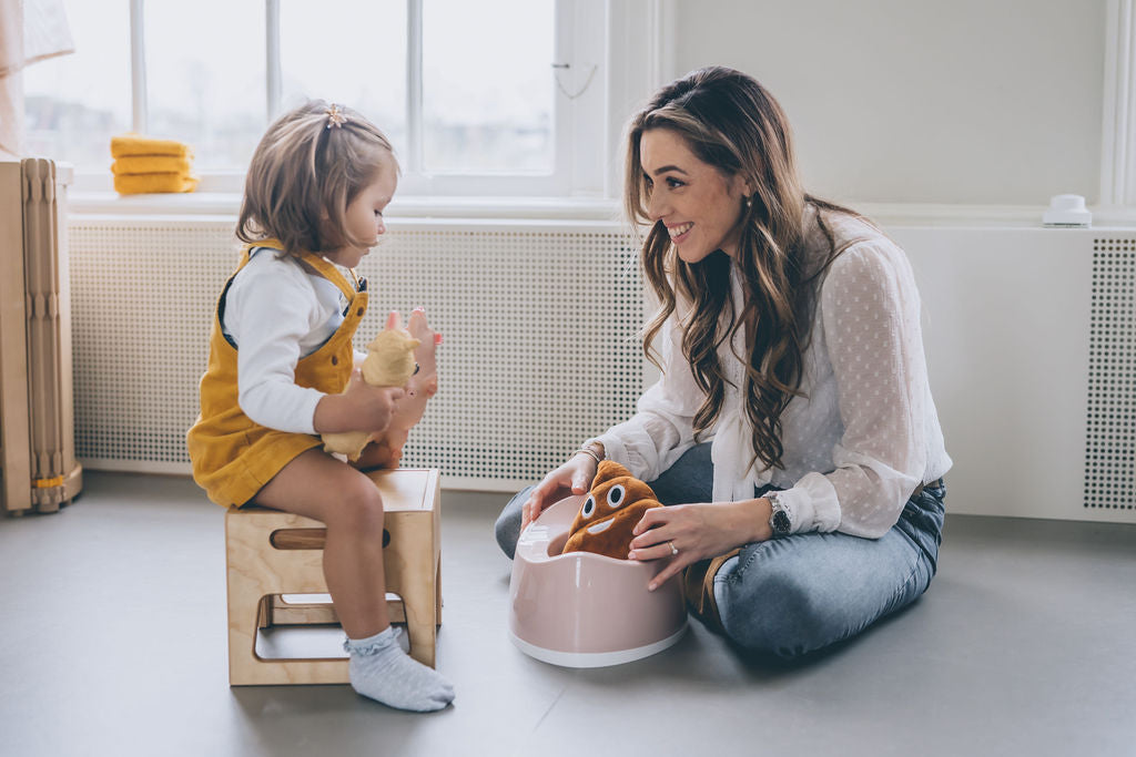 Parent helping toddler during potty training.