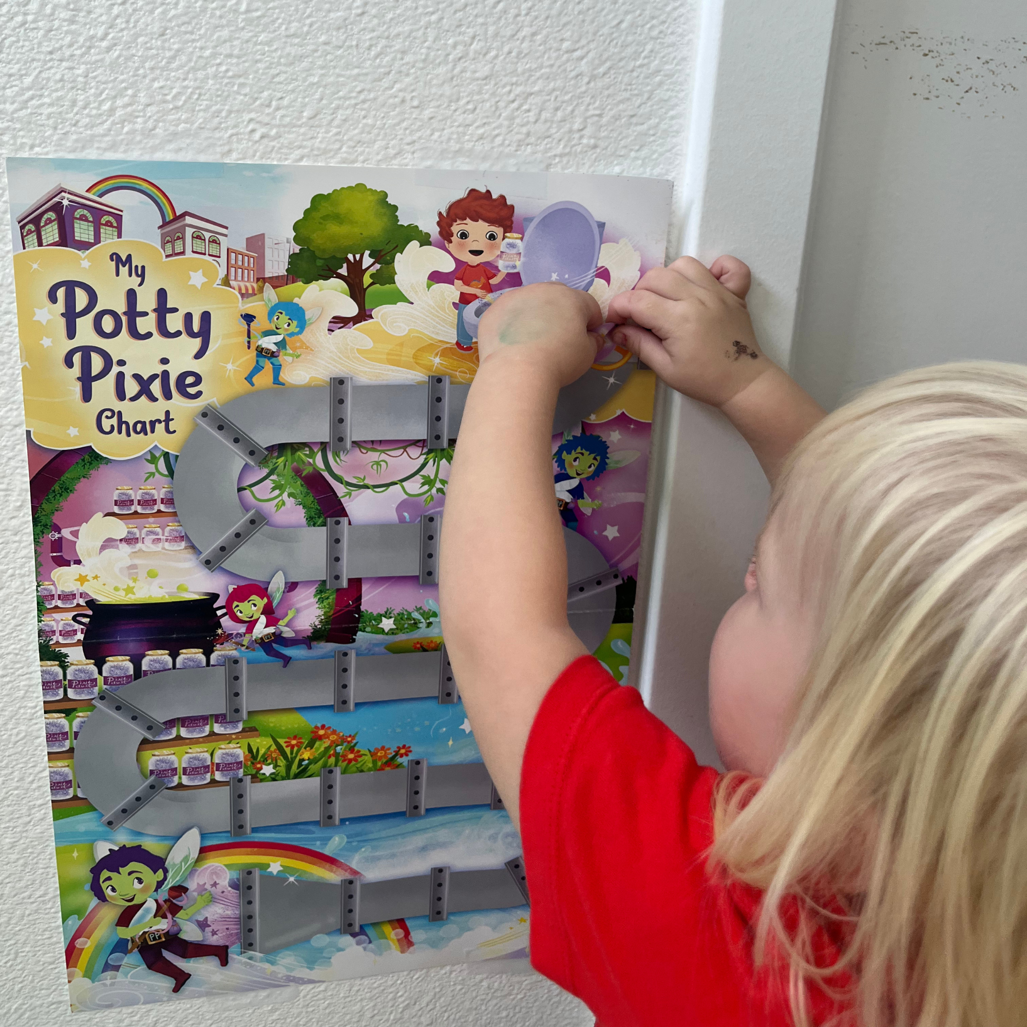 Child interacting with a colorful potty training chart on a wall.