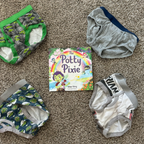 Potty training products including training pants and a book titled 'The Potty Pixie' on a carpeted floor. Ready for undies?!