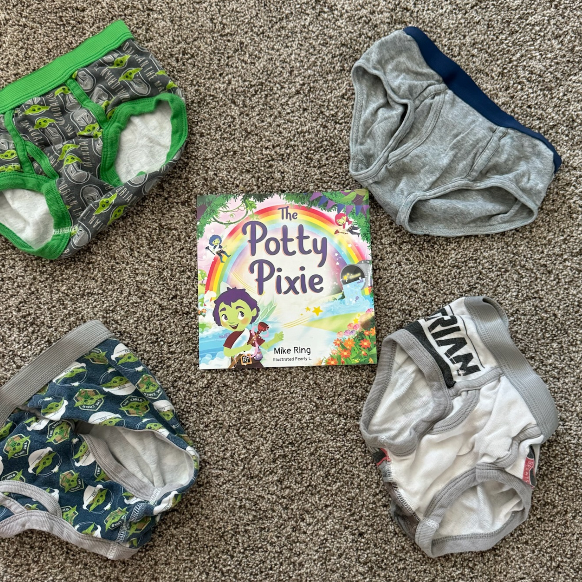 Potty training products including training pants and a book titled 'The Potty Pixie' on a carpeted floor. Ready for undies?!